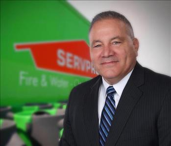 Man in suit in front of a SERVPRO trailer backdrop